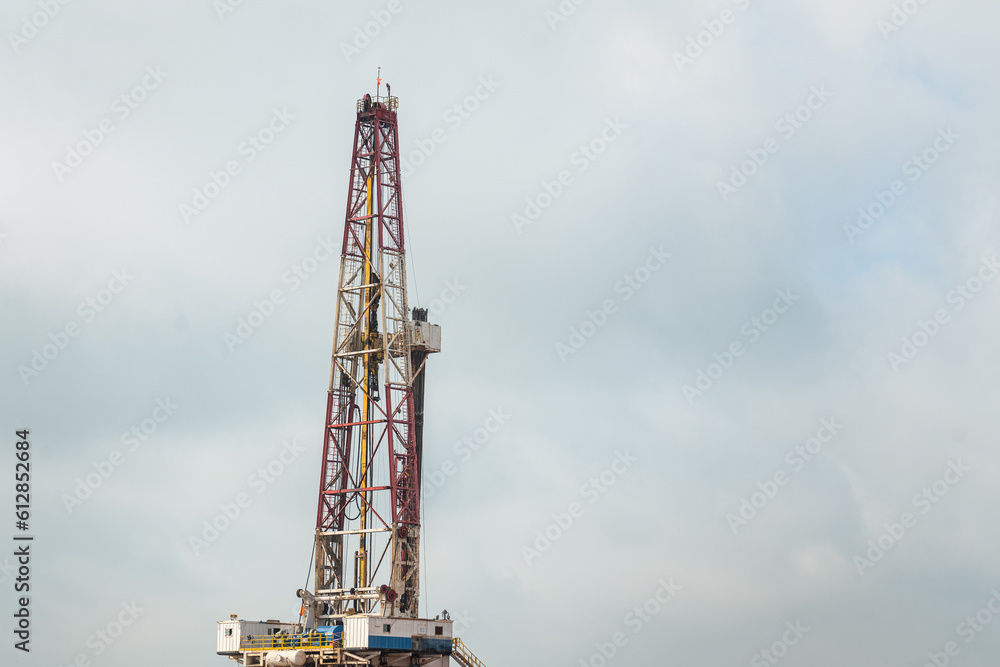 The oil drilling rig derrick structure on cloudy sky background, oil field industrial operation equipment. Selective focus. The oil drilling rig derrick structure on cloudy sky background, oil field industrial operation equipment. Selective focus.
