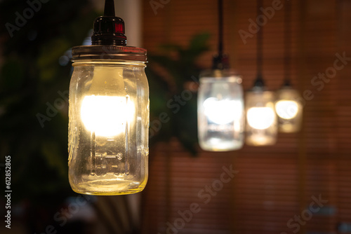 Row of glowing lightng bulbs in glasses that installed as ceiling lamp. Interior object decoration for cozy style photo, selective focus at from. photo