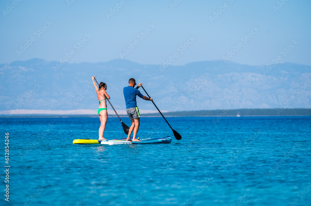 Naklejka premium Couple riding SUP stand up paddle on vacation.