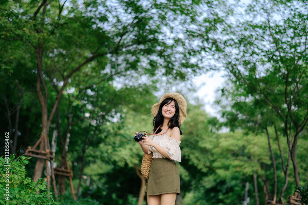 Portrait of asian young woman traveler with weaving hat and basket and a camera on green public park nature background. Journey trip lifestyle, world travel explorer or Asia summer tourism concept. Portrait of asian young woman traveler with weaving hat and basket and a camera on green public park nature background. Journey trip lifestyle, world travel explorer or Asia summer tourism concept.