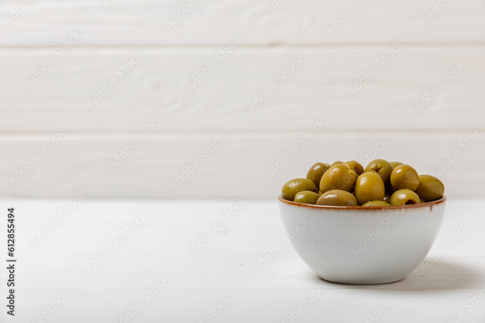 Green olives on a white wooden background. Various types of olives in bowls and olive oil with fresh olive leaves. Copy space. Place for text. Mediterranean food. Vegan. Green olives on a white wooden background. Various types of olives in bowls and olive oil with fresh olive leaves. Copy space. Place for text. Mediterranean food. Vegan.