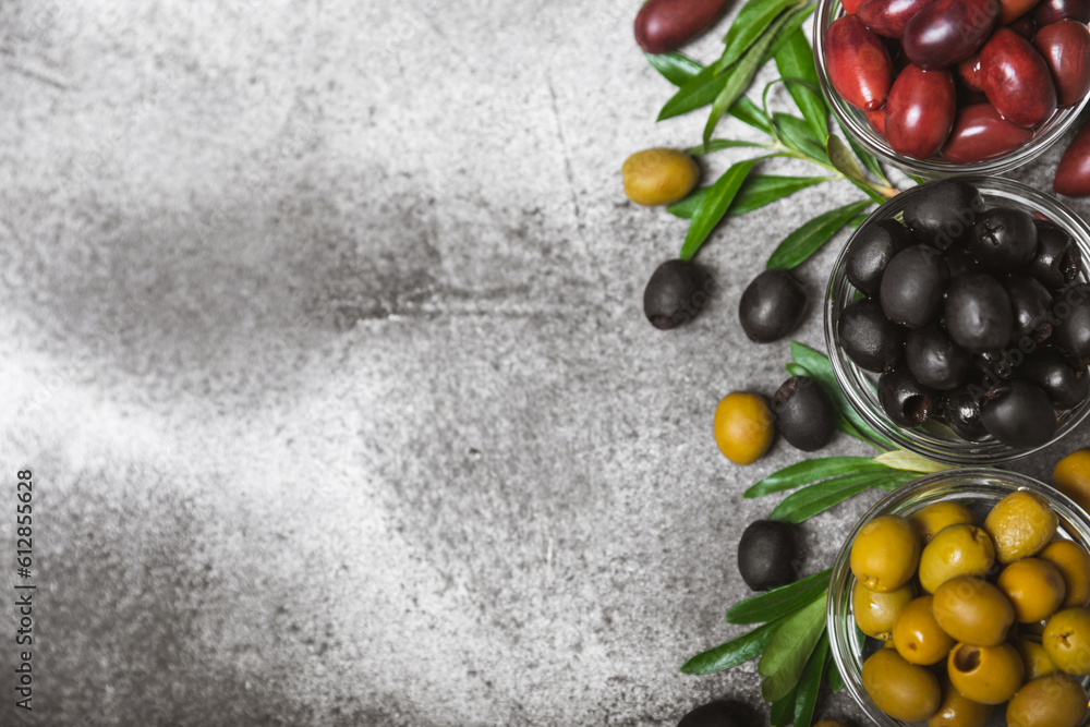 Green, black and red olives on a textured marble background. Various types of olives in bowls and olive oil with fresh olive leaves. Copy space. Place for text. Mediterranean food. Vegan. Green, black and red olives on a textured marble background. Various types of olives in bowls and olive oil with fresh olive leaves. Copy space. Place for text. Mediterranean food. Vegan.