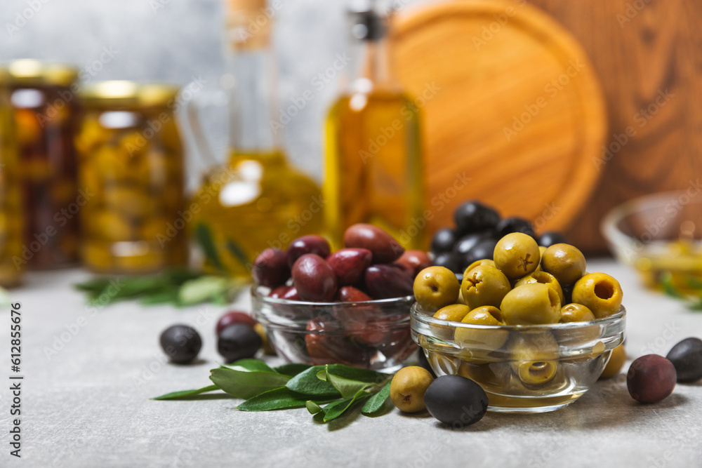 Green, black and red olives on a textured marble background. Various types of olives in bowls and olive oil with fresh olive leaves. Copy space. Place for text. Mediterranean food. Vegan. Green, black and red olives on a textured marble background. Various types of olives in bowls and olive oil with fresh olive leaves. Copy space. Place for text. Mediterranean food. Vegan.