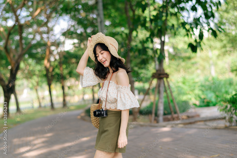 Portrait of asian young woman traveler with weaving hat and basket and a camera on green public park nature background. Journey trip lifestyle, world travel explorer or Asia summer tourism concept. Portrait of asian young woman traveler with weaving hat and basket and a camera on green public park nature background. Journey trip lifestyle, world travel explorer or Asia summer tourism concept.