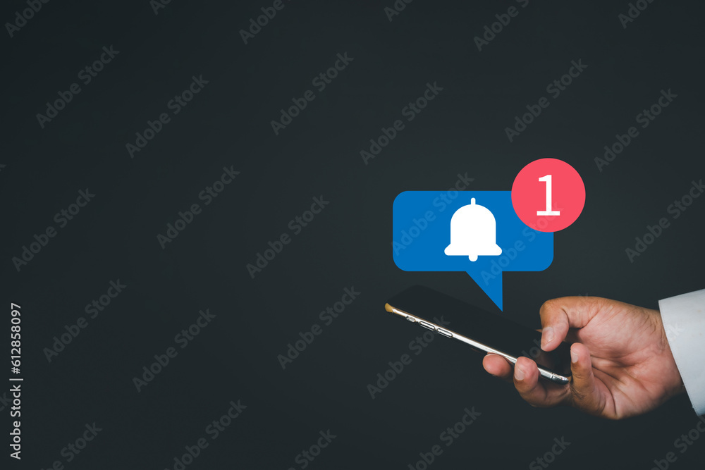 Reminder,digital marketing,business concept.,Close up of hand using smartphone with Bell Notification icon on black background with copyspace suitable for internet,application,e-mail,technology idea. Reminder,digital marketing,business concept.,Close up of hand using smartphone with Bell Notification icon on black background with copyspace suitable for internet,application,e-mail,technology idea.