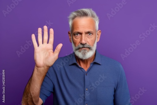 Medium shot portrait photography of a tender mature man making a sorry gesture with hands together against a vibrant purple background. With generative AI technology