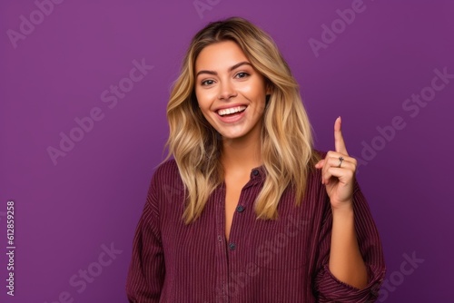 Headshot portrait photography of a happy girl in her 20s pointing empty space against a vibrant purple background. With generative AI technology