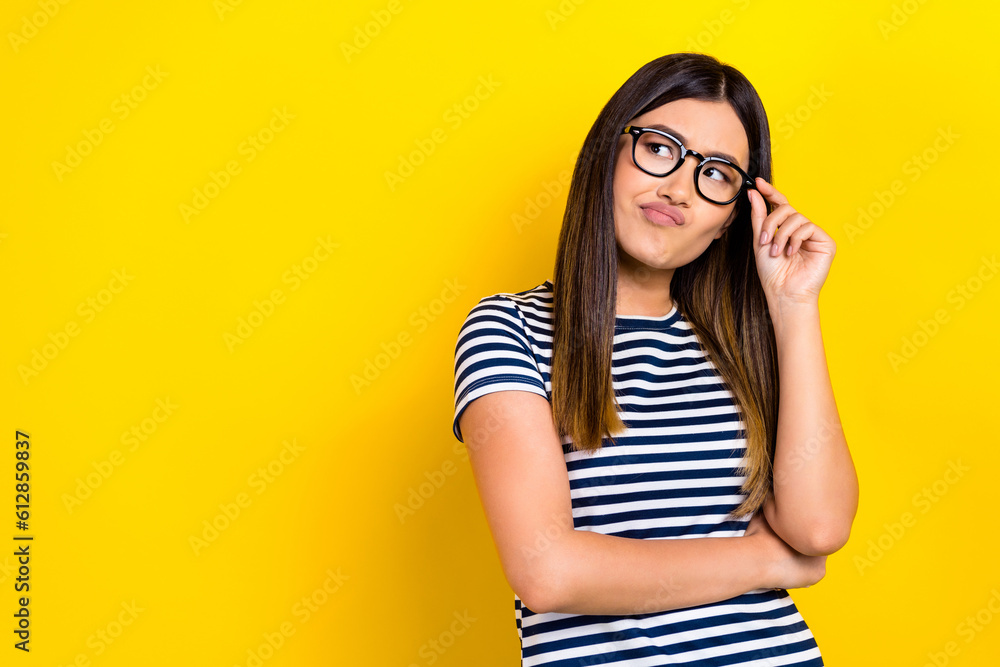 Portrait of beautiful business girl wear striped t-shirt hold eyeglasses look suspicious product choice isolated on yellow color background Portrait of beautiful business girl wear striped t-shirt hold eyeglasses look suspicious product choice isolated on yellow color background