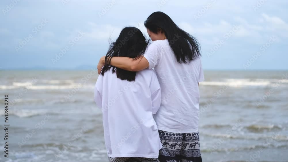 Asian mother and daughter hugging by the sea on vacation