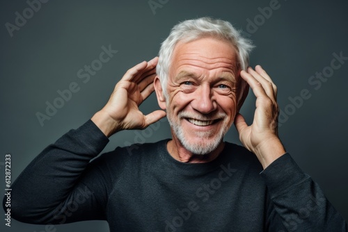 Headshot portrait photography of a joyful mature man making a i'm listening gesture with the hand on the ear against a metallic silver background. With generative AI technology