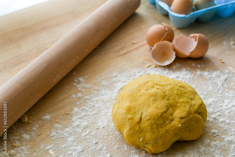 Ball of raw pasta dough with eggshells, egg carton, and rolling pin in the background Ball of raw pasta dough with eggshells, egg carton, and rolling pin in the background