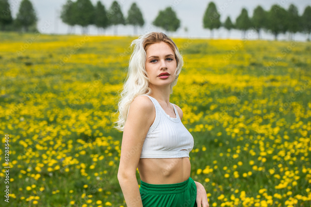 Young beautiful blonde woman posing in a spring field of dandelions Young beautiful blonde woman posing in a spring field of dandelions