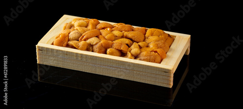 Bafun urchin or uni in wooden box on dark background, Uni sushi or sashimi ingredients, Japanese style photo