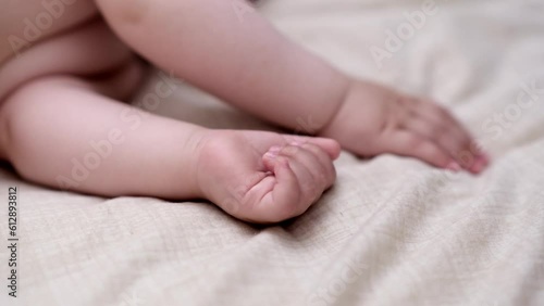 Tiny hand and fingers of little boy sleeping on soft bed with white sheet in nursery at home adorable baby taking nap in afternoon after breastfeeding closeup photo