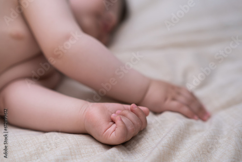 Innocent little boy sleeping in crib grabbing soft white sheet with tiny hands adorable infant baby enjoying relaxing in cozy nursery after breastfeeding in morning closeup