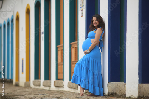 Maternidade em destaque: imagem de uma gestante feliz, vestindo um lindo vestido azul, em um ensaio fotográfico realizado em Paraty.