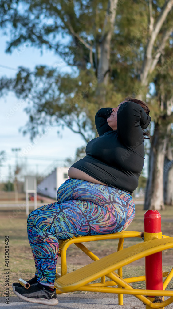 Young fat woman doing abs workout in the park by the lake. Healthy lifestyle Young fat woman doing abs workout in the park by the lake. Healthy lifestyle
