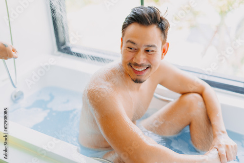 Happy childish disable asian man being take care of showering by his wife.