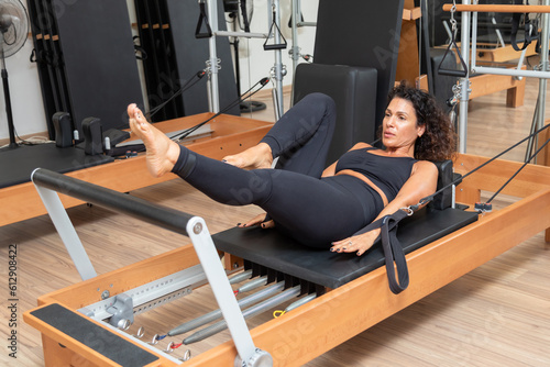 Young woman exercising on pilates reformers beds