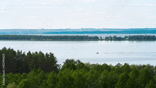 A full-flowing plain river with a motorboat rushing through the water.