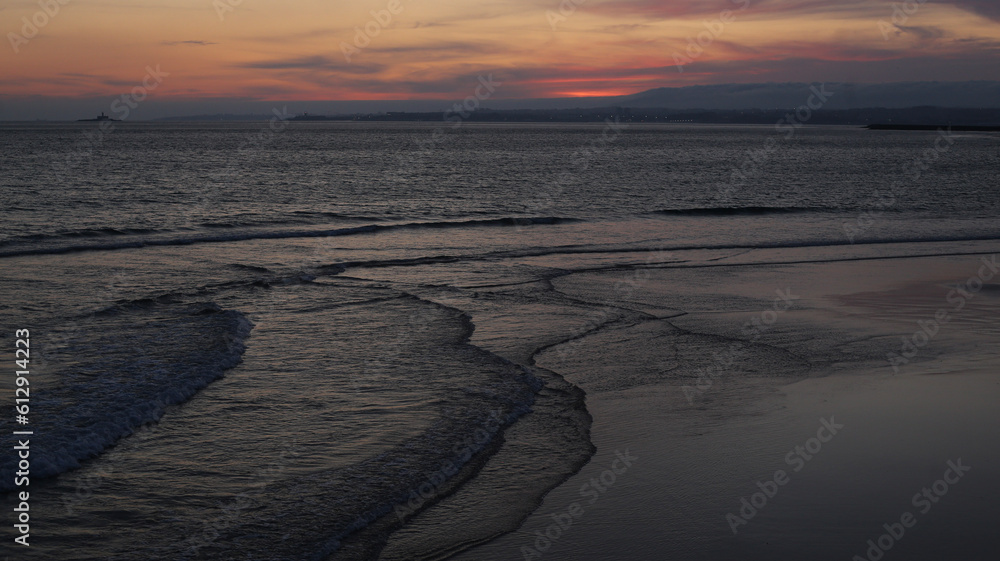 Fototapeta premium Cores do entardecer: imagem capturada após o pôr do sol, revelando as últimas tonalidades coloridas do dia na praia da Costa da Caparica.