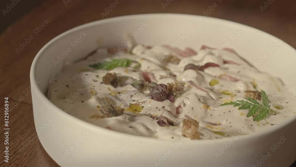 No people closeup of delicious creamy ravioli with parmesan sauce and olive oil in white bowl on wooden table No people closeup of delicious creamy ravioli with parmesan sauce and olive oil in white bowl on wooden table
