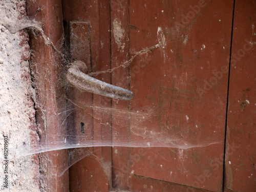 La maniglia del portone di una casa disabitata, invaso dalle ragnatele photo