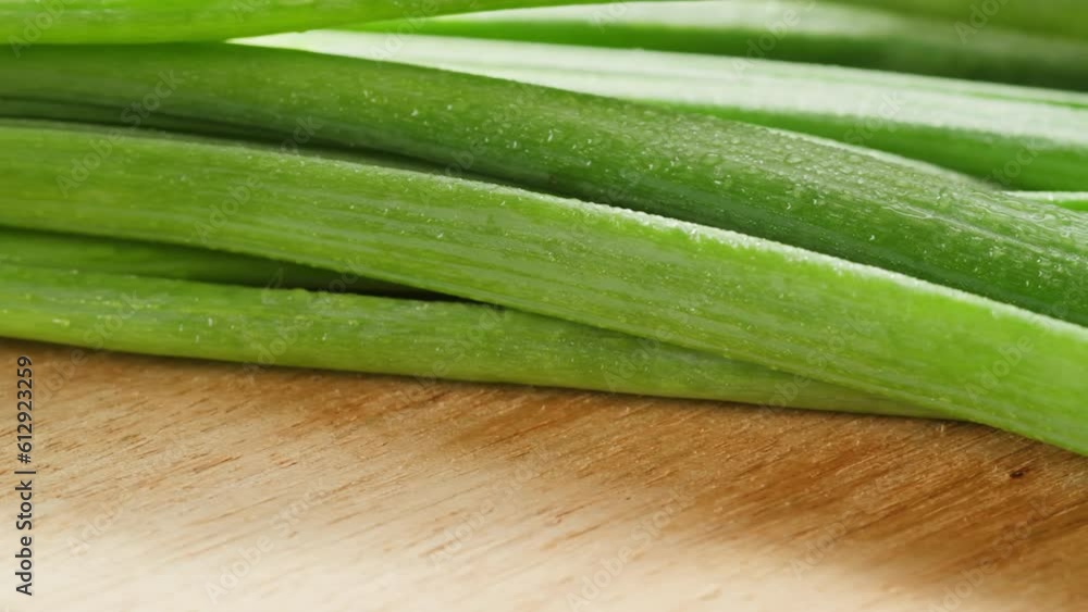 Bunch of green onion feathers with drops of water on a cutting board, Close-up macro rotating shot. Bunch of green onion feathers with drops of water on a cutting board, Close-up macro rotating shot.