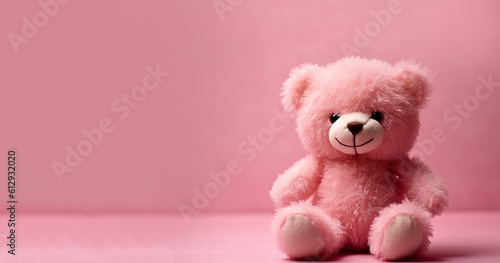 Cute smiling pink teddy bear doll in pink room. Background with shadow reflection. Playful bright pink bear sitting. Teddy bear plush stuffed puppet with ribbon on white backdrop. copy space