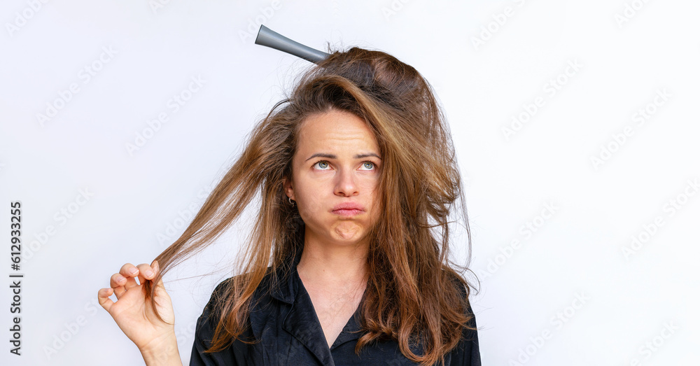 Sad woman combing styling tangled dry  weak hair on a white background. - obrazy, fototapety, plakaty 