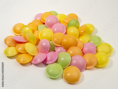 Sweet candies in the shape of a UFO in different colors on a white background. Flying saucers sugar paper in the shape of a spaceship with sherbet.