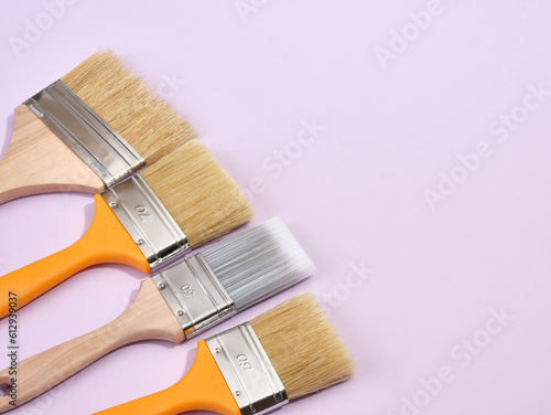 Brushes for painting walls, floors and other surfaces when repairing lie on a purple background. Copy space for text.