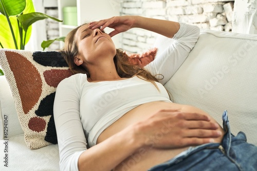 Foto Restless pregnant woman on sofa, seeking comfort amid discomfort.