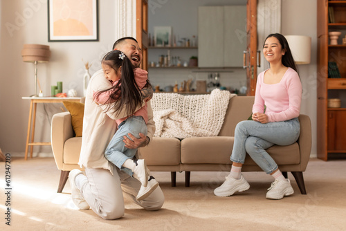 Foto Korean Baby Hugging Daddy, Mother Looking At Them At Home