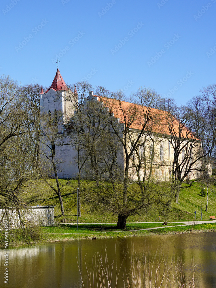 Fototapeta premium Springtime view through the trees to the Evangelical Lutheran Church of Aizpute, Latvia