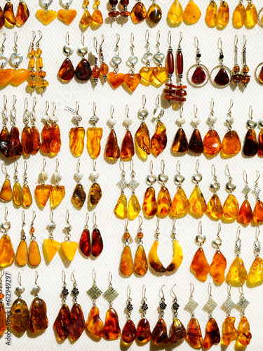 Light background with lots of yellow, golden, honey and brown natural amber earrings in silver
