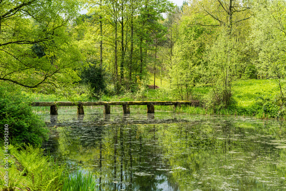Fototapeta premium Old stone slab granite bridge across a pond or calm lake in English park land