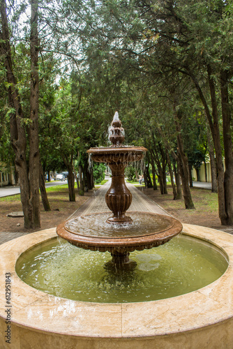 Pyatigorsk, Stavropol Territory, Russia - July, 25, 2022: Fountain on a green alley in the old resort town on a summer day and green trees