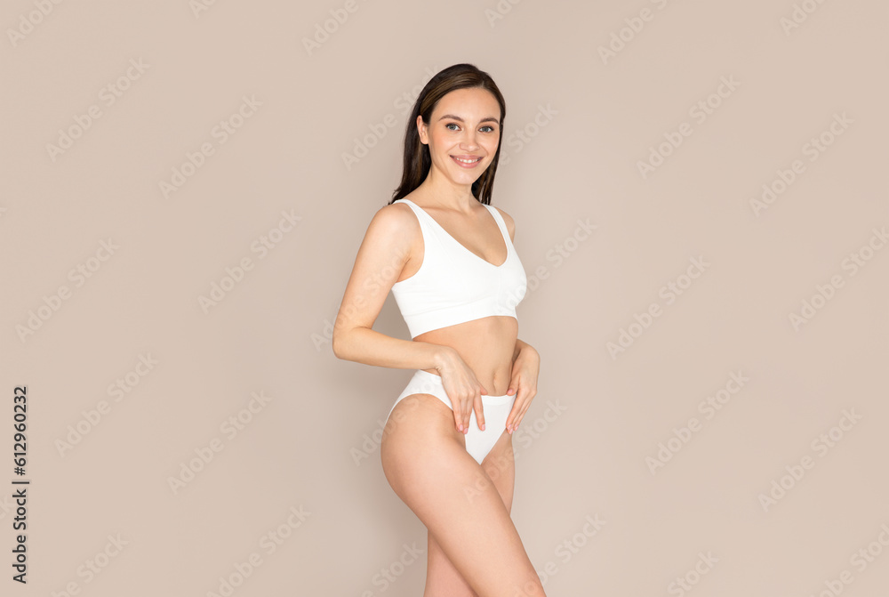 Happy beautiful woman posing on beige background in comfortable underwear Happy beautiful woman posing on beige background in comfortable underwear