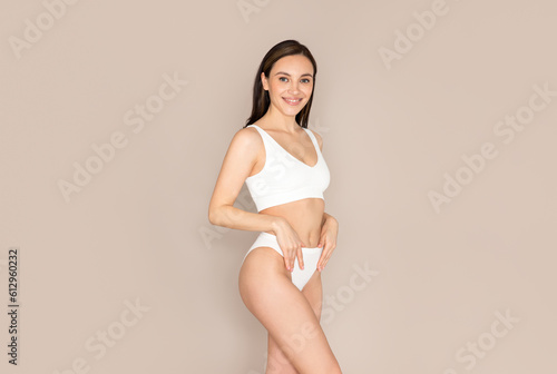 Happy beautiful woman posing on beige background in comfortable underwear