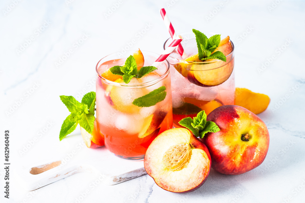 Peach cocktail, iced peach tea, fruit drink, summer beverage with fresh fruits and mint. Close up. Peach cocktail, iced peach tea, fruit drink, summer beverage with fresh fruits and mint. Close up.