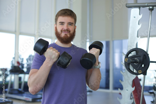 Young happy athletic man is training in the gym doing exercise with barbell