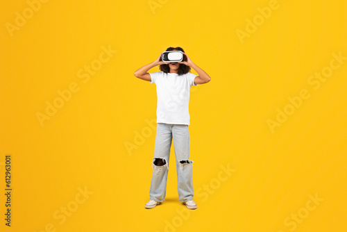 Glad curly teenager black schoolgirl in white t-shirt and vr glasses plays online game © Prostock-studio