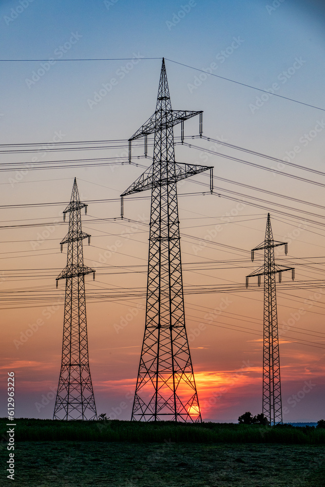 Sonnenuntergang hinter Strommasten einer Überlandleitung