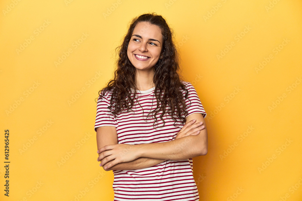 Young Caucasian woman, yellow studio background, smiling confident with crossed arms. Young Caucasian woman, yellow studio background, smiling confident with crossed arms.