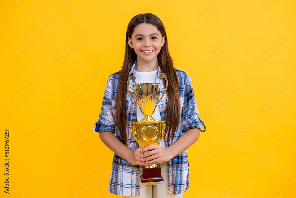 cheerful teen girl hold her award champion cup isolated on yellow. teen girl receive award in studio. teen girl accept award on background. proud teen girl with champion cup award cheerful teen girl hold her award champion cup isolated on yellow. teen girl receive award in studio. teen girl accept award on background. proud teen girl with champion cup award