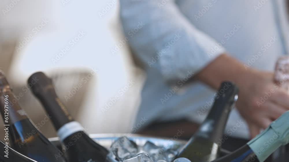 A person takes a bottle of champagne from a bucket filled with ice A person takes a bottle of champagne from a bucket filled with ice