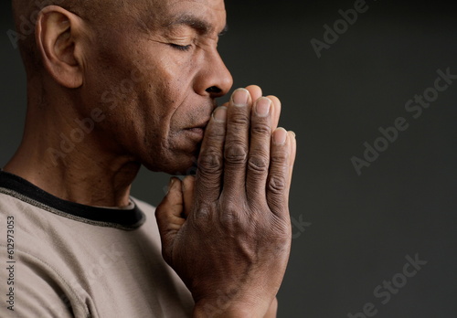 man praying to god with hands together Caribbean man praying on black background with people stock photos stock photo 