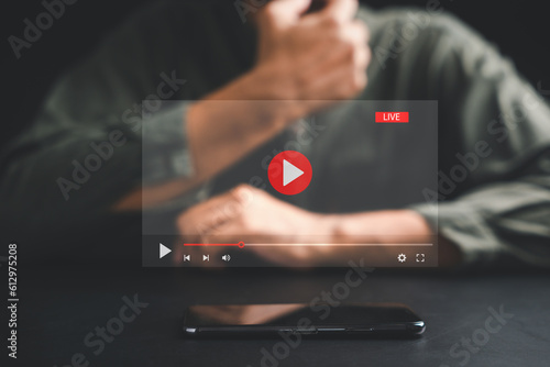Man initiates live streaming on a smartphone, captivated by the video streaming and multimedia displayed on the screen. Embrace the fusion of technology and lifestyle in the realm of social media.