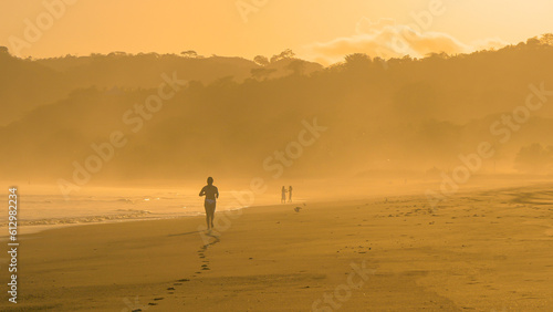 Unrecognizable sporty female person jogging in golden sunlight at Playa Venao